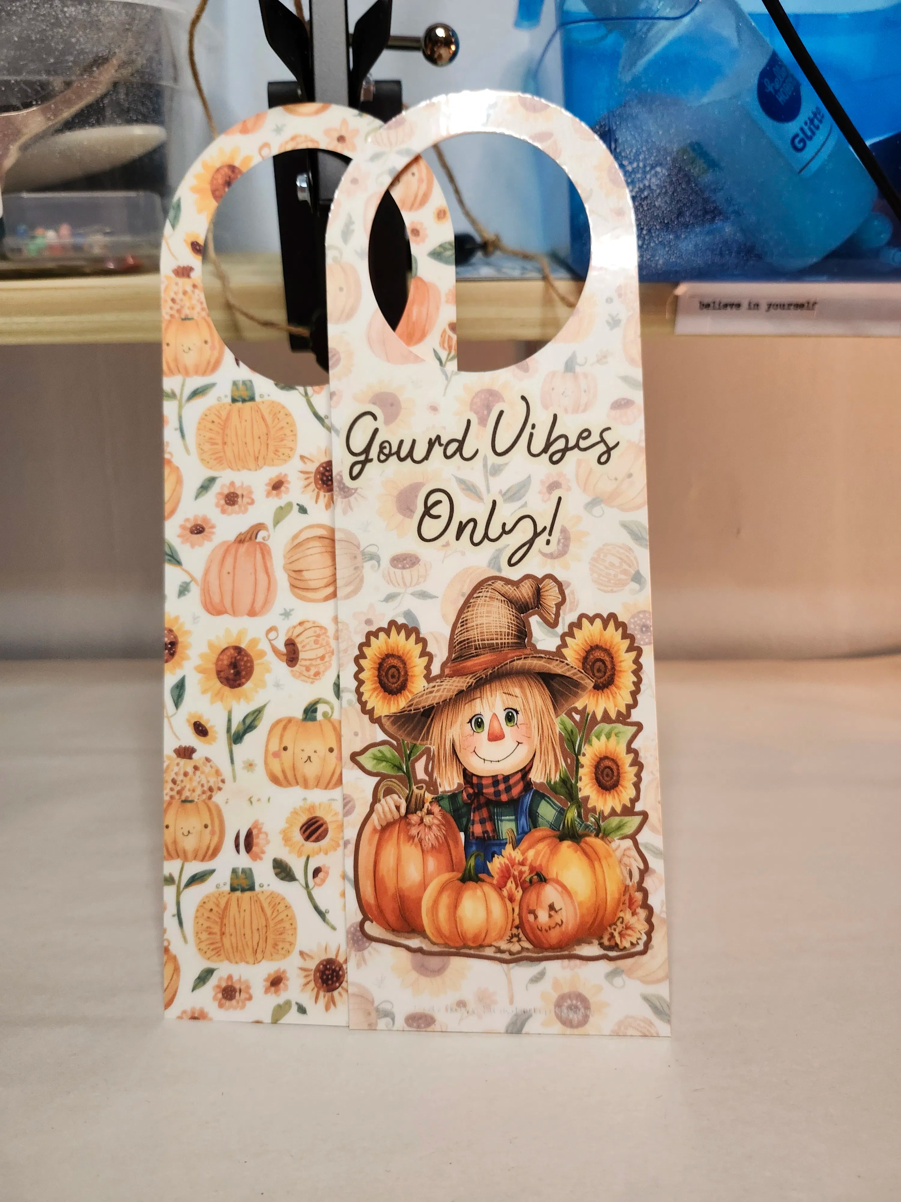 Decorative door hanger with scarecrow, pumpkins, and sunflowers on a neutral background.