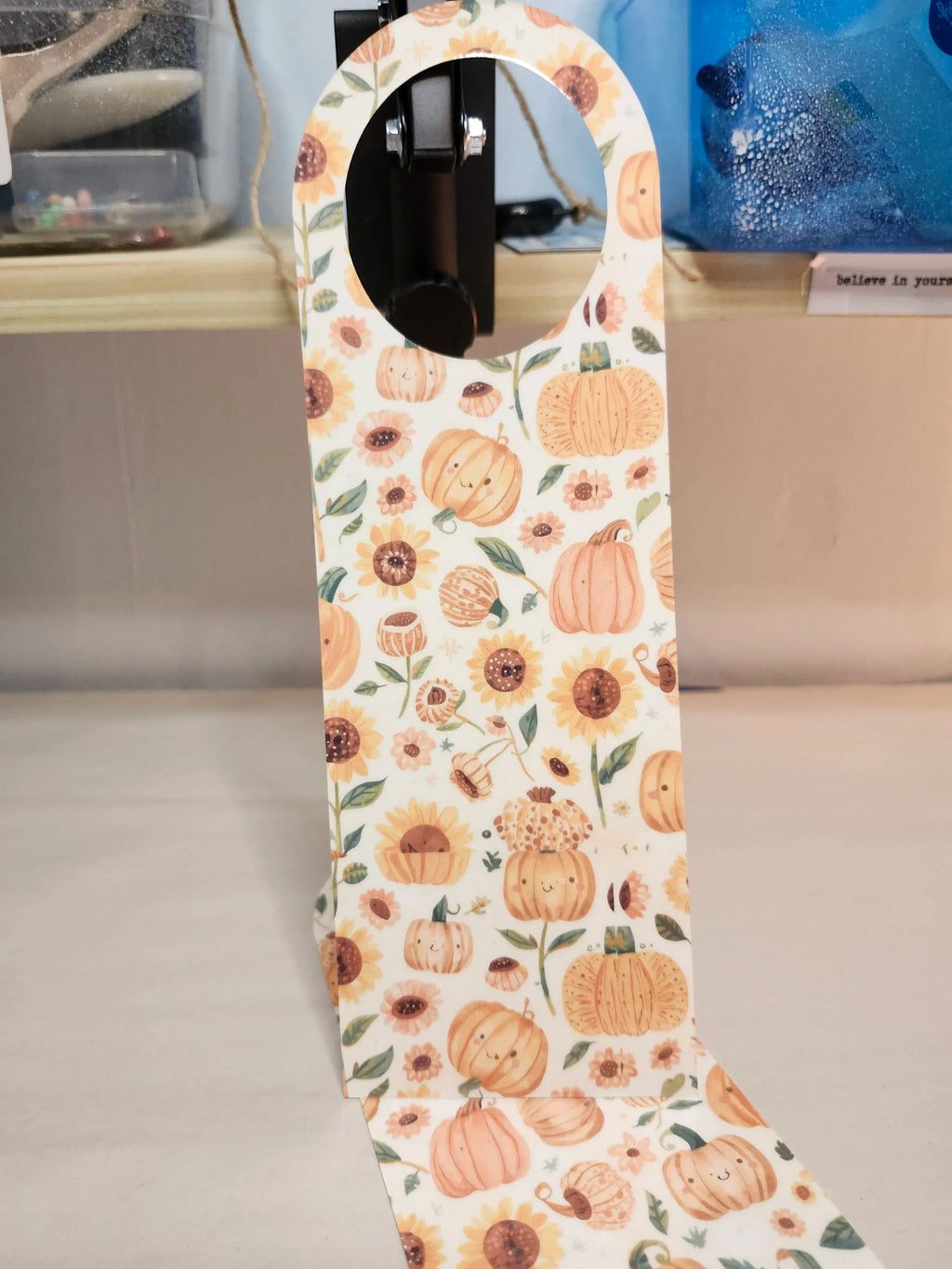 Decorative ironing board cover with pumpkin and sunflower pattern on a surface.