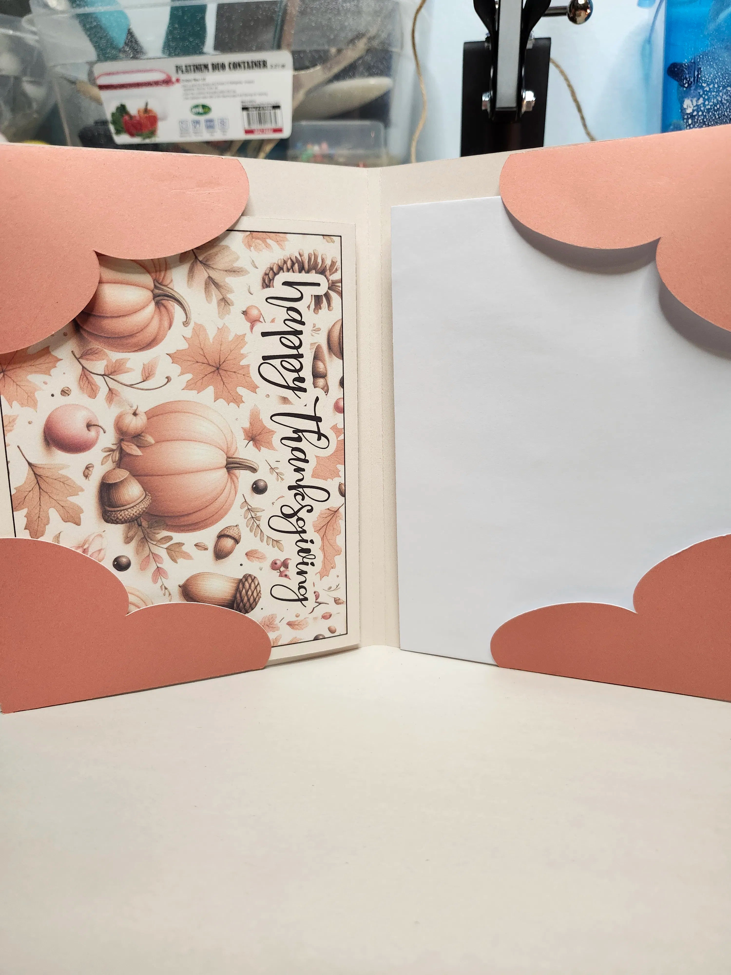 Open card with autumn-themed design featuring pumpkins and leaves, on a light surface.