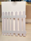 White picket fence card on a wooden surface
