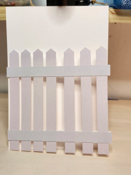 White picket fence card on a wooden surface
