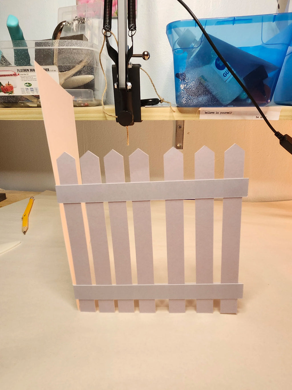 Small white picket fence on a light surface with a blurred background