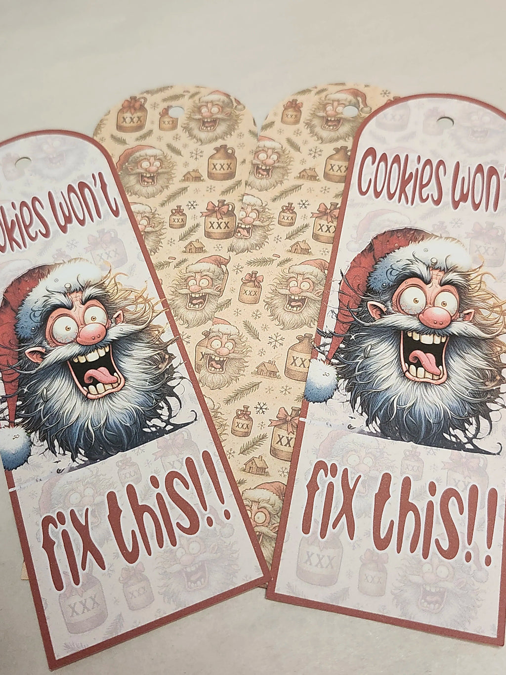 Two festive gift tags with a cartoon Santa Claus and text 'Cookies won't fix this!!' on a patterned background.