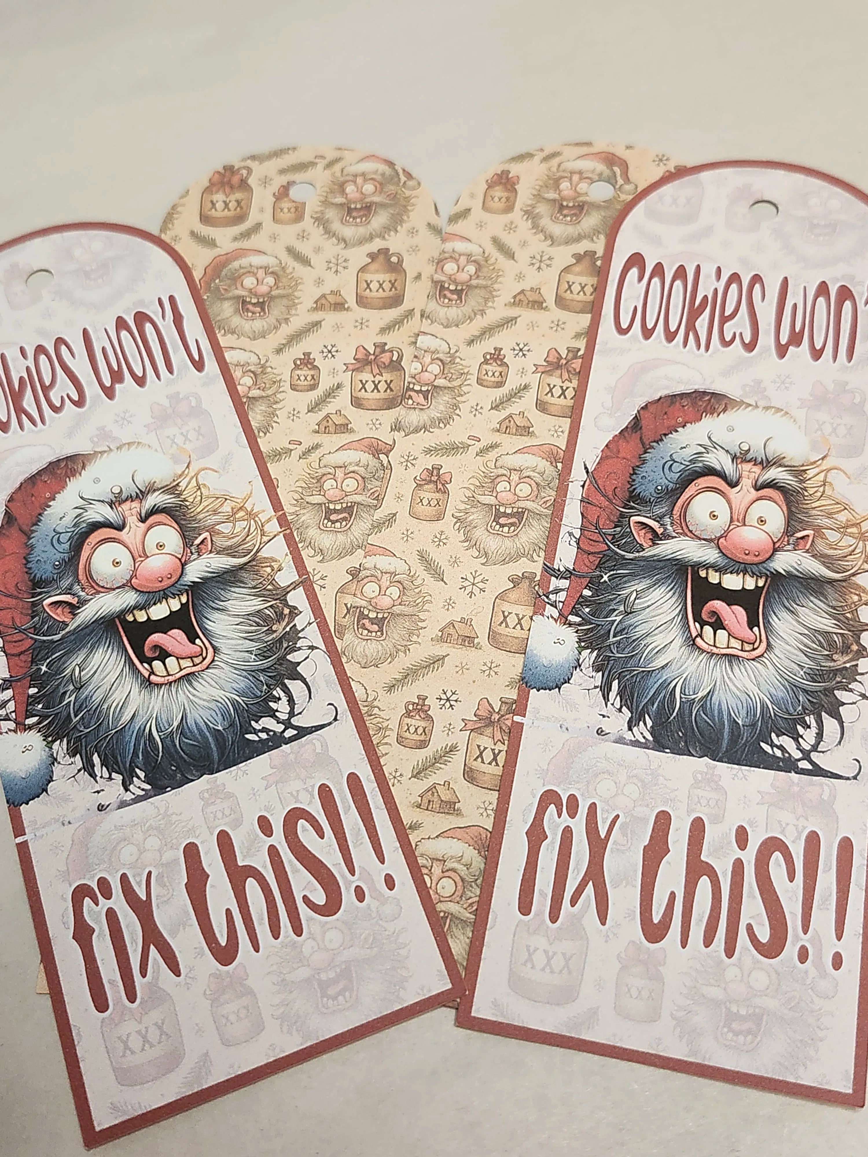 Two festive gift tags with a cartoon Santa Claus and text 'Cookies won't fix this!!' on a patterned background.