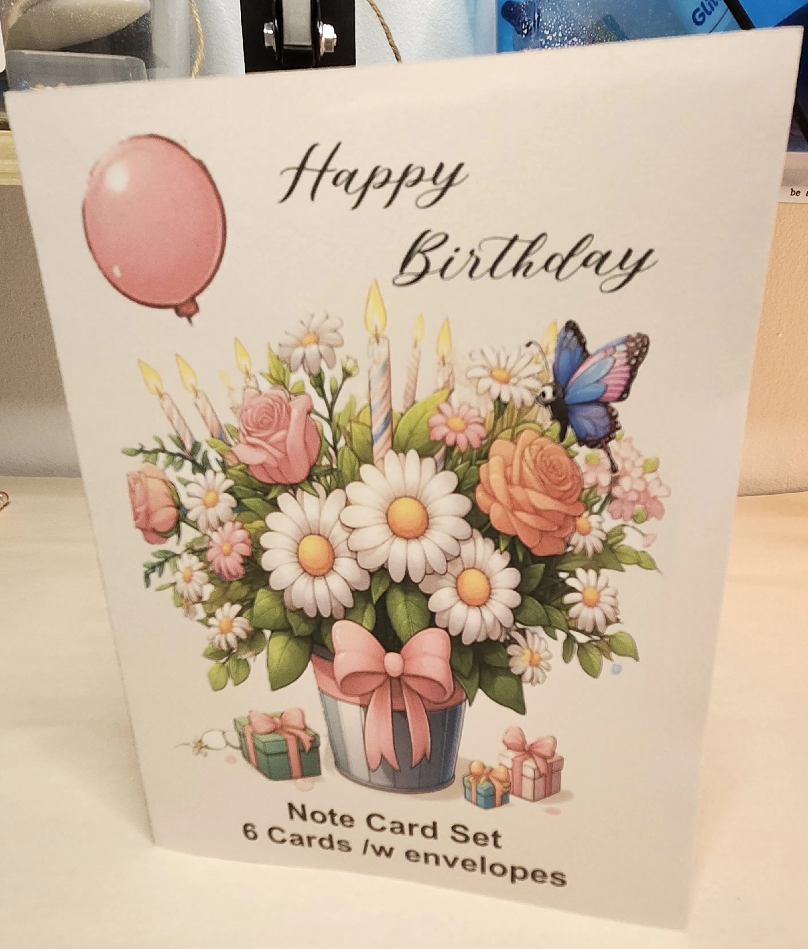 Packaging of a birthday card set with flowers, balloons, and a butterfly on a white background.