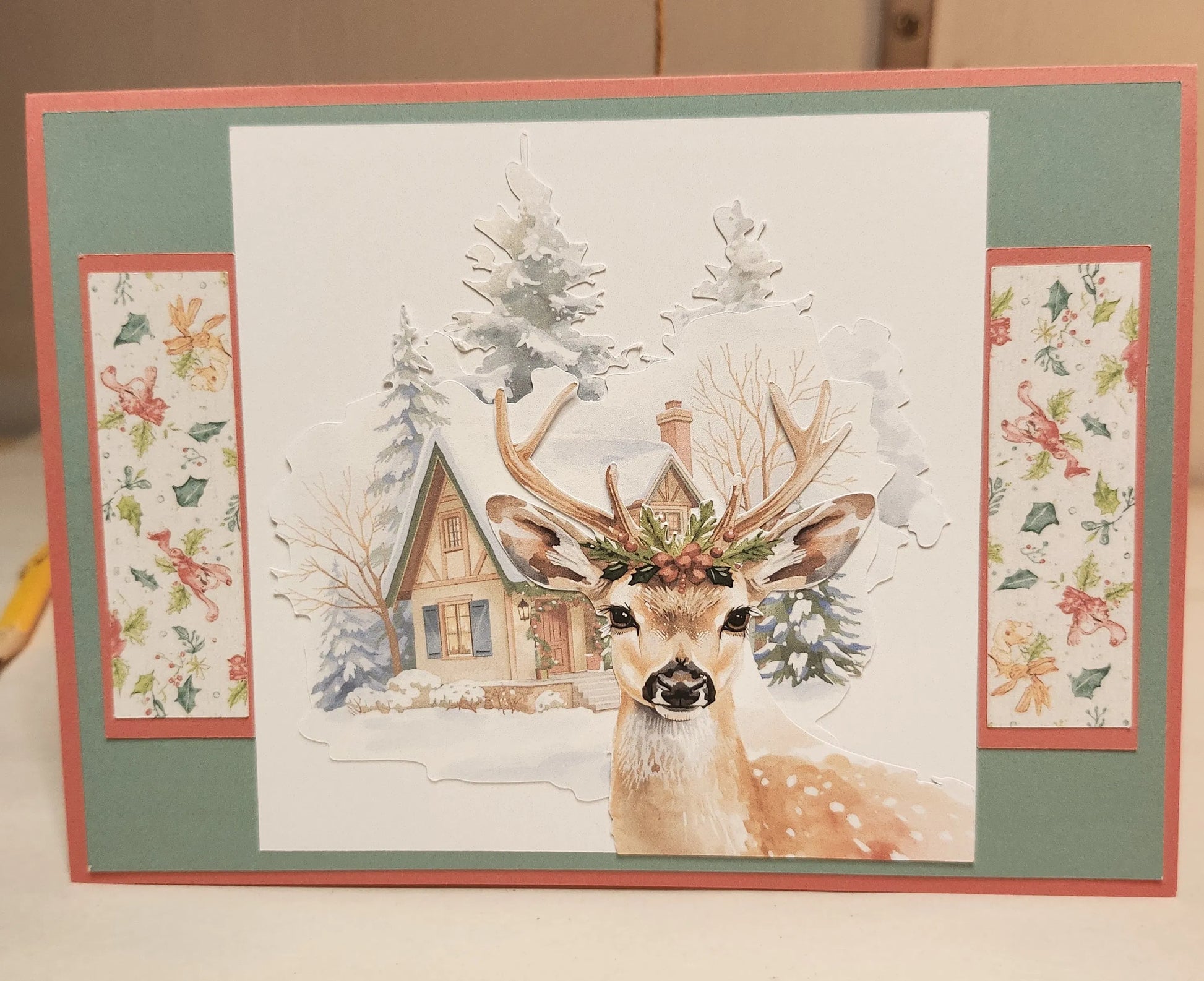 Card with a deer illustration and snowy cabin in a decorative frame.