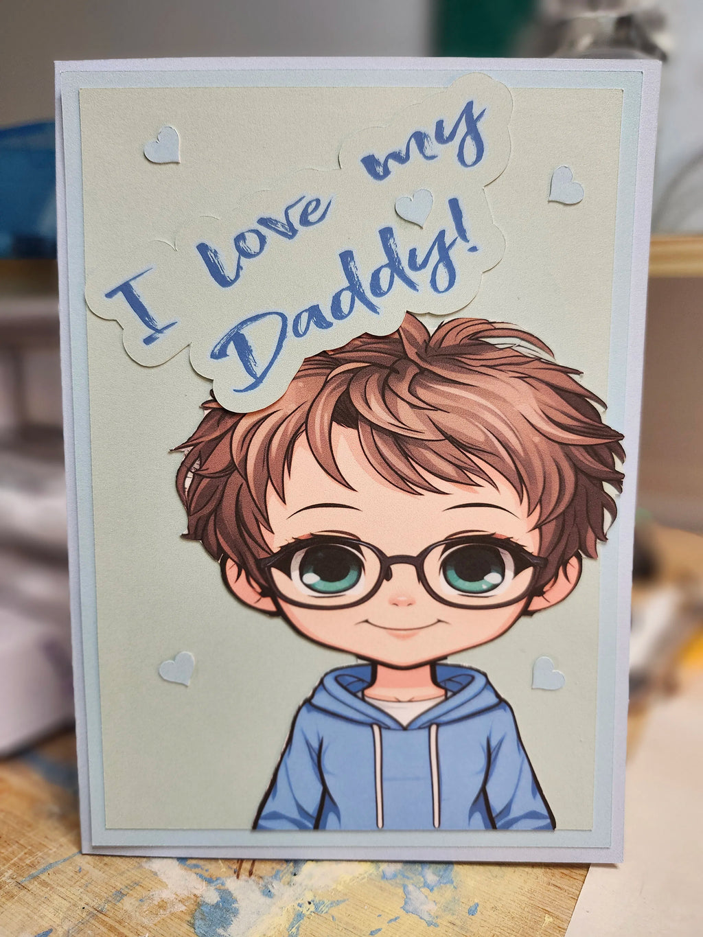 Card with a cartoon boy wearing glasses and text 'I love my Daddy!' on a neutral background.