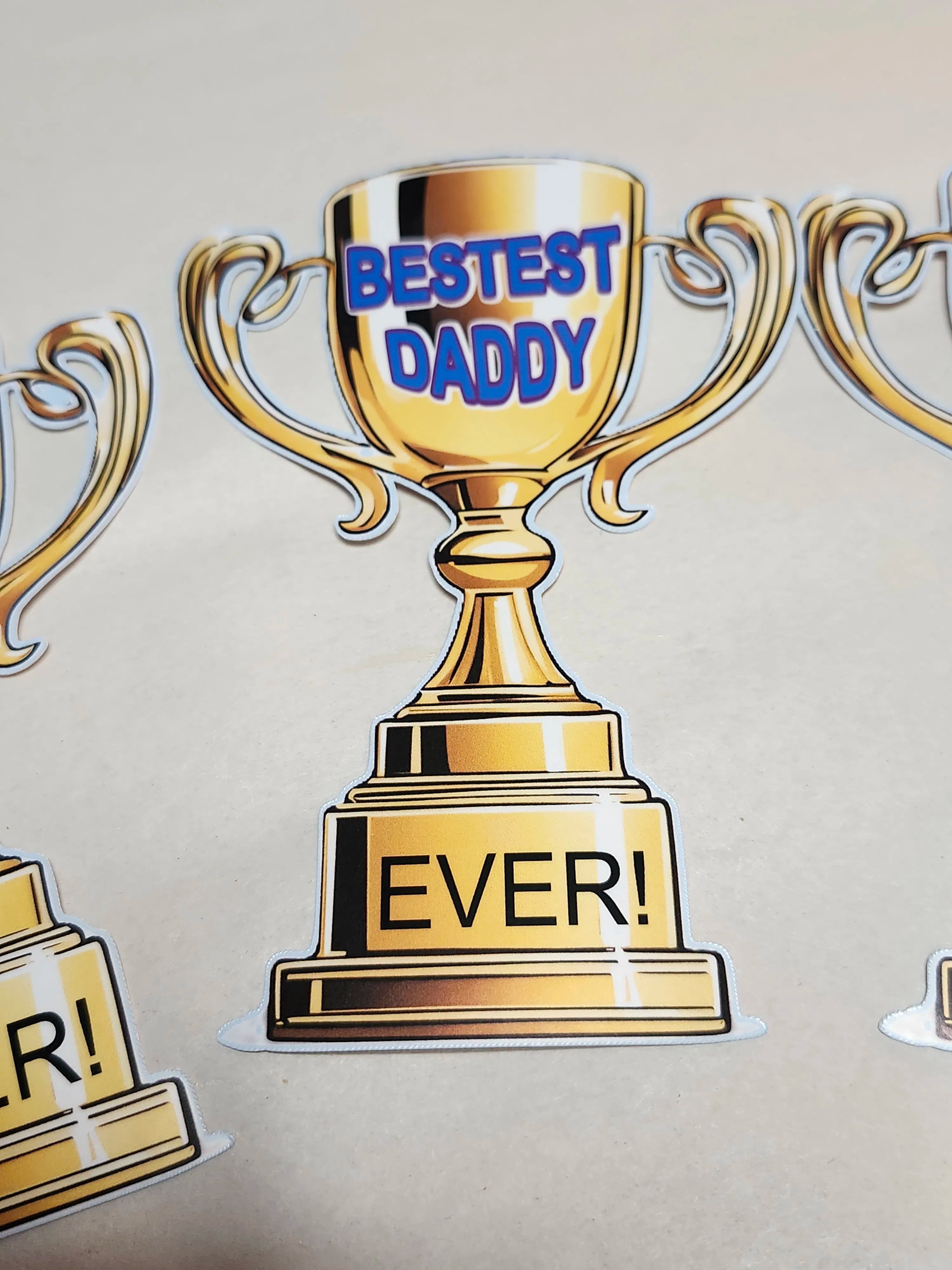 Gold trophy with 'Bestest Daddy Ever!' text on a beige background