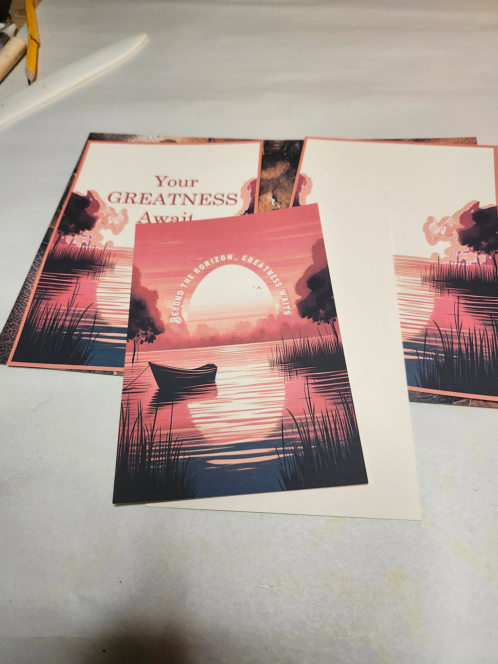 Three posters with sunset and nature designs on a flat surface.