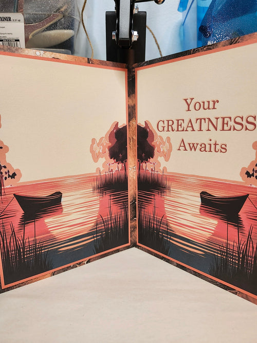 Card with silhouette design of boats and trees, featuring text 'Your GREATNESS Awaits'.