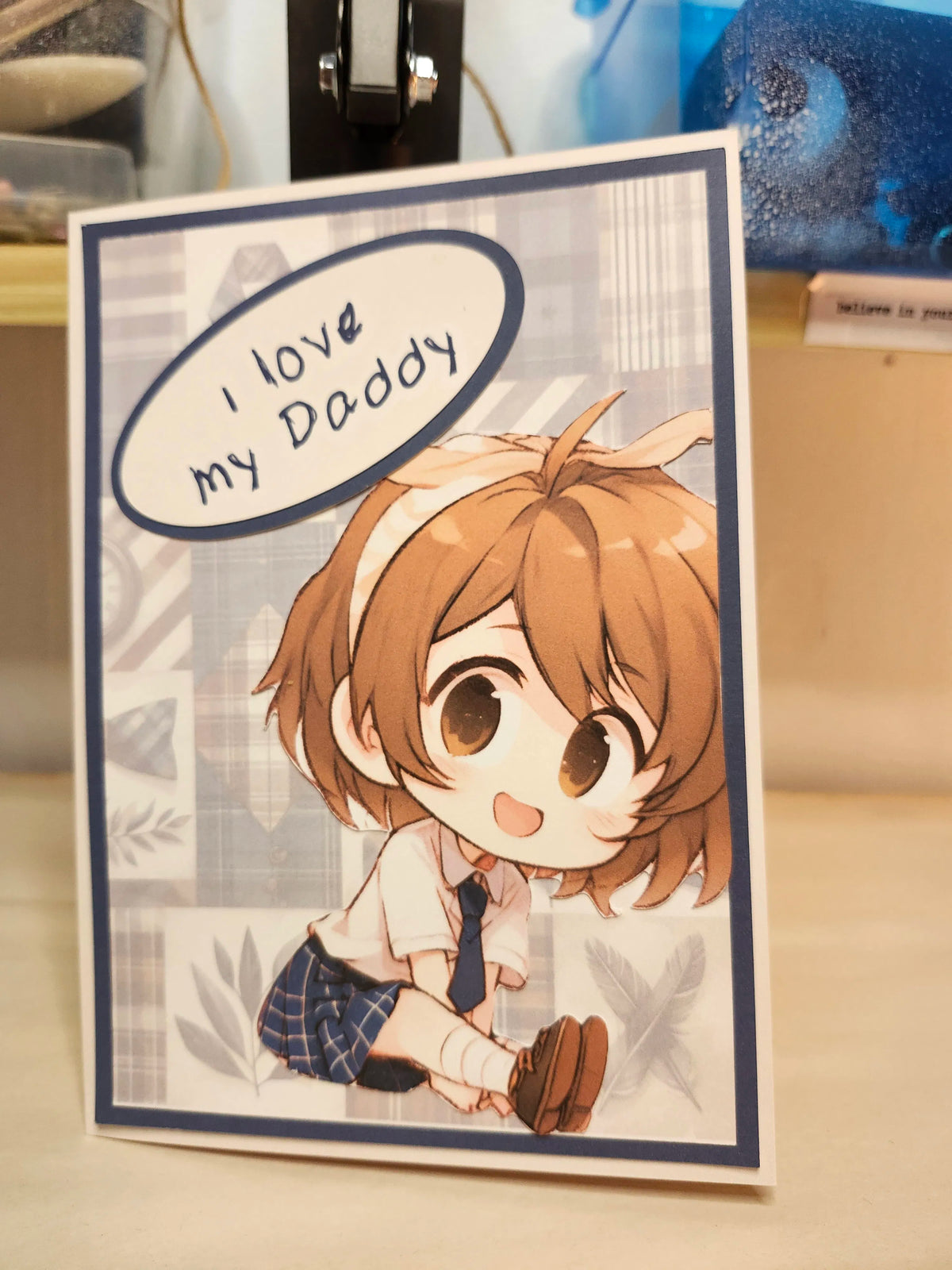 Card with a cartoon character and 'I love my Daddy' text on a wooden surface.