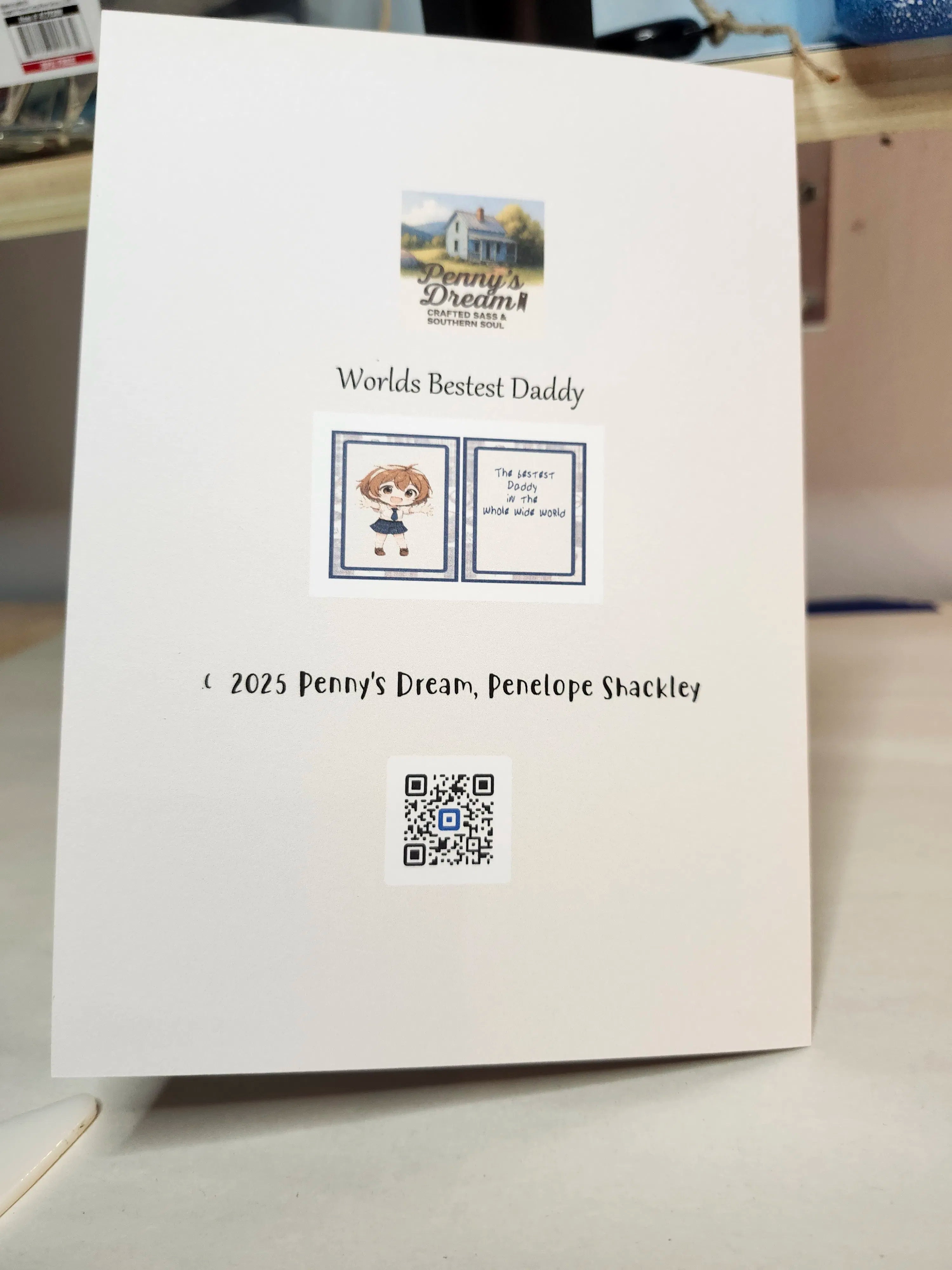 Card with 'Worlds Bestest Daddy' text and a QR code on a white surface.