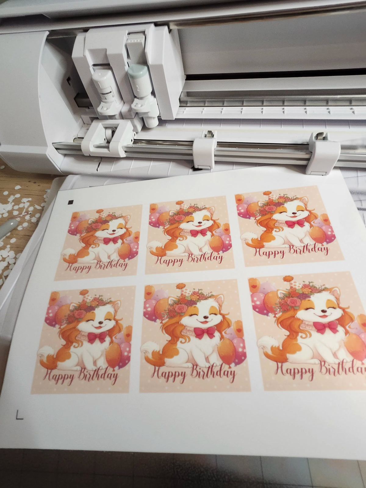 Cricut machine with printed 'Happy Birthday' cards featuring cartoon bears.