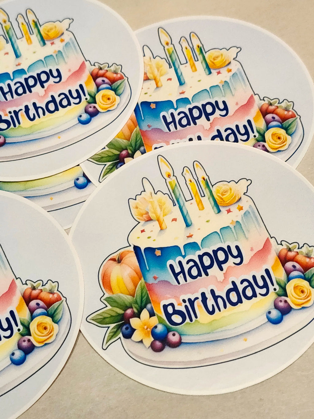 Colorful 'Happy Birthday!' cake stickers with candles and flowers on a beige background.