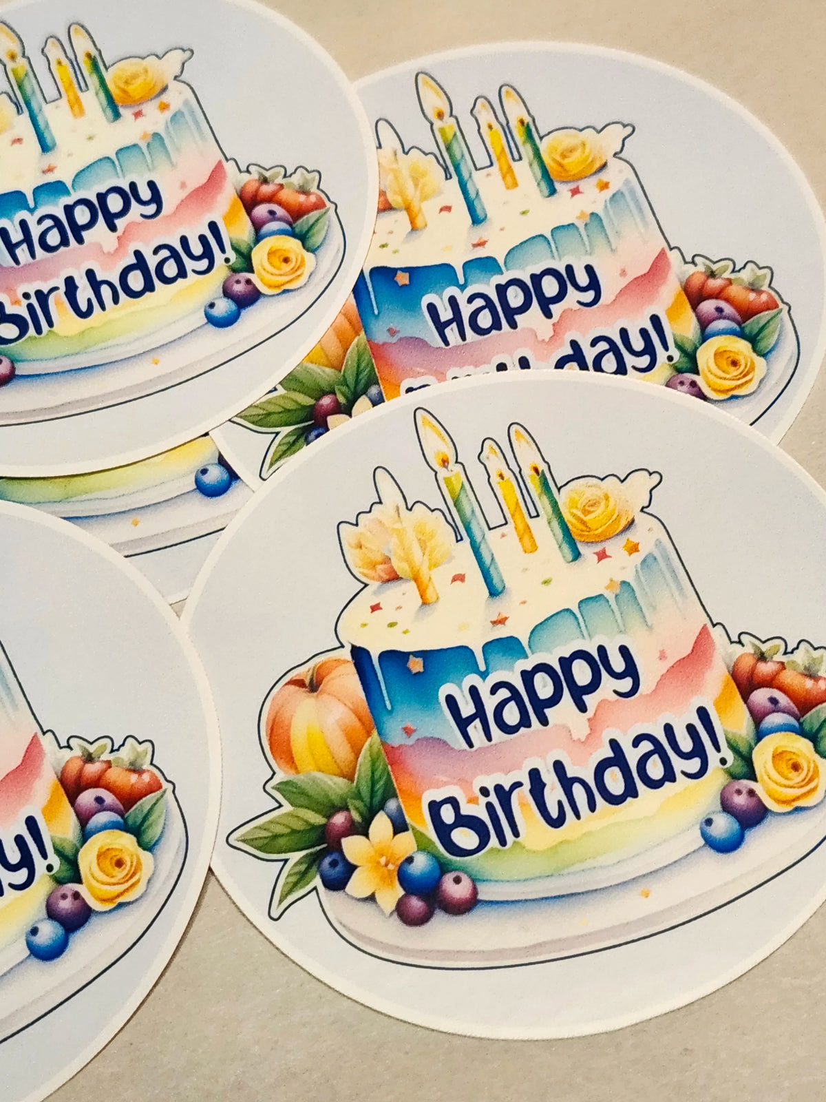 Colorful 'Happy Birthday!' cake stickers with candles and flowers on a beige background.