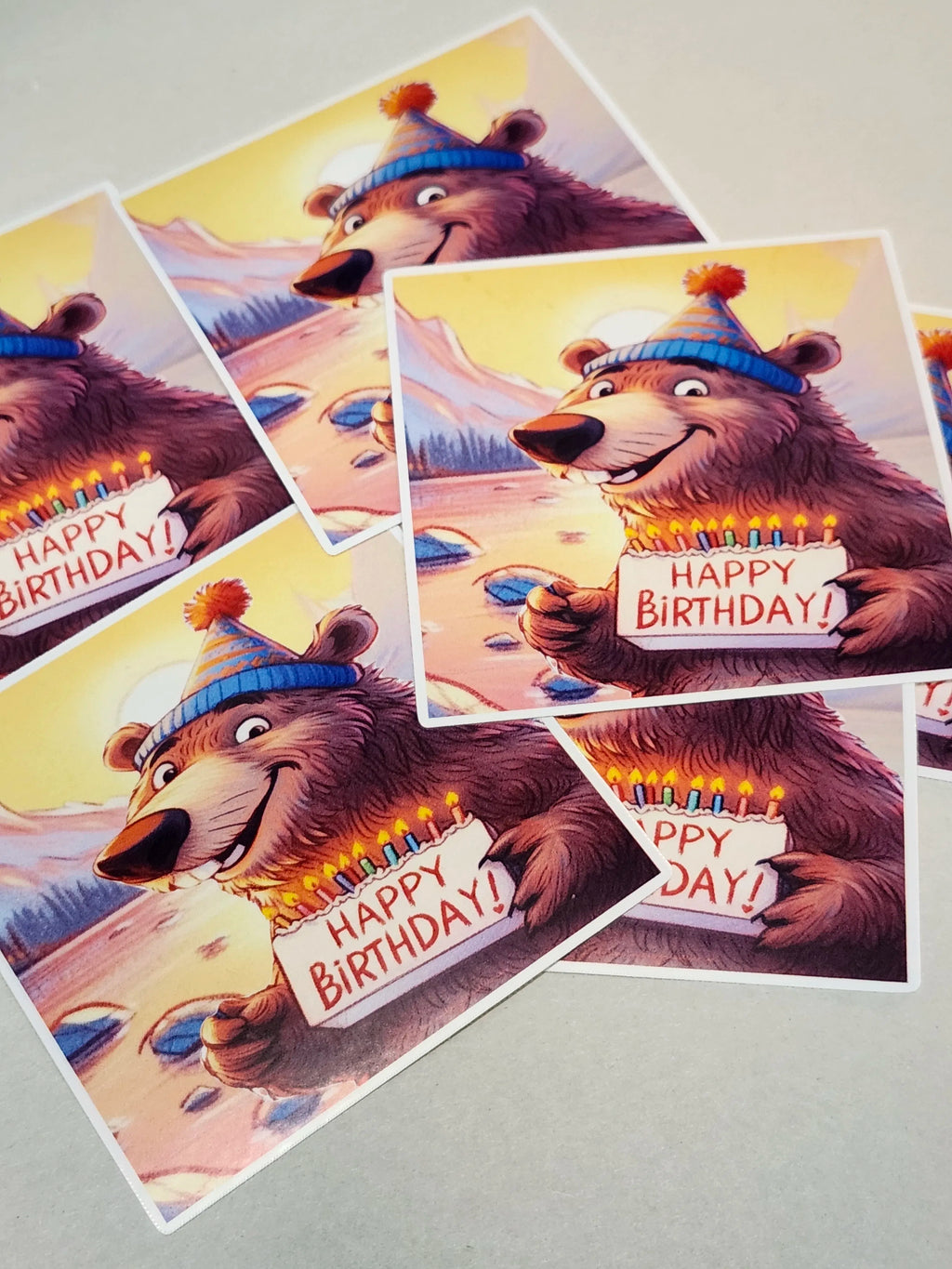 Set of birthday cards with a bear holding a cake and 'Happy Birthday!' sign on a gray background