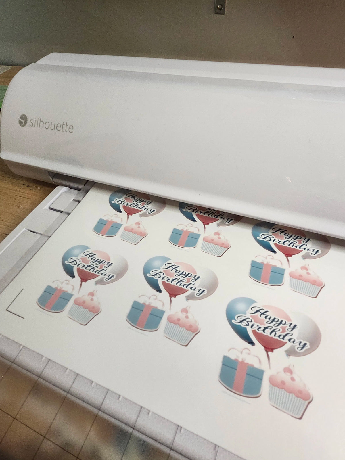 Silhouette cutting machine with printed 'Happy Birthday' stickers on a mat