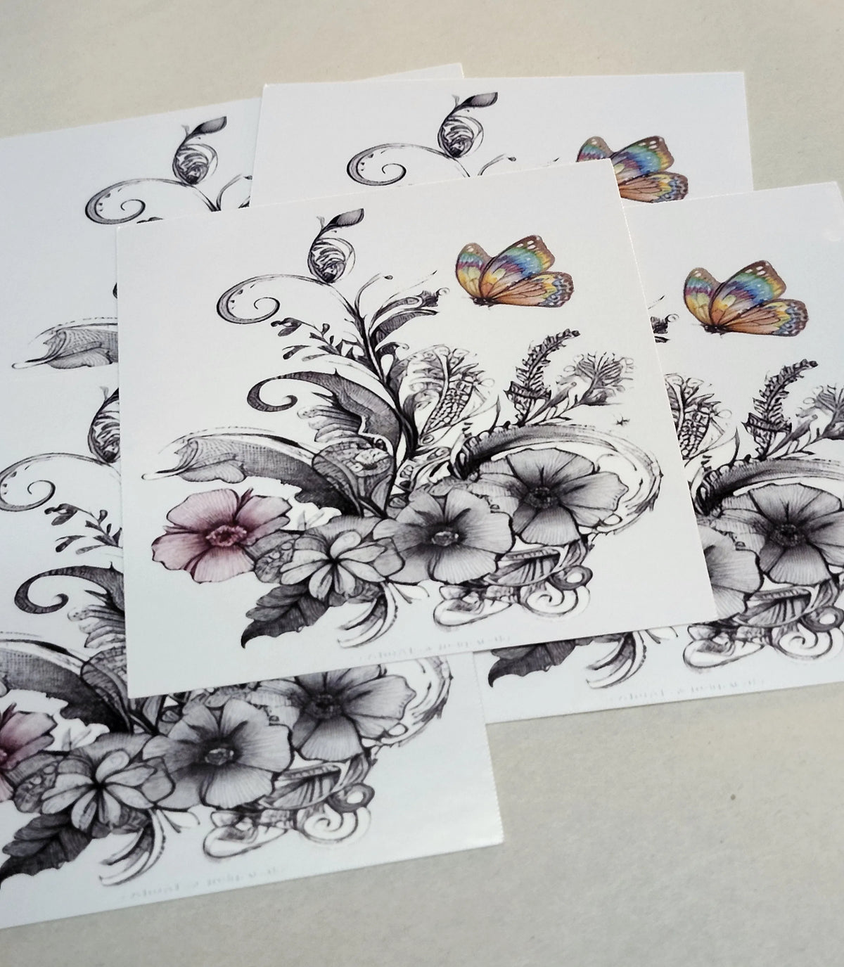 Floral and butterfly temporary tattoos on white paper with a beige background