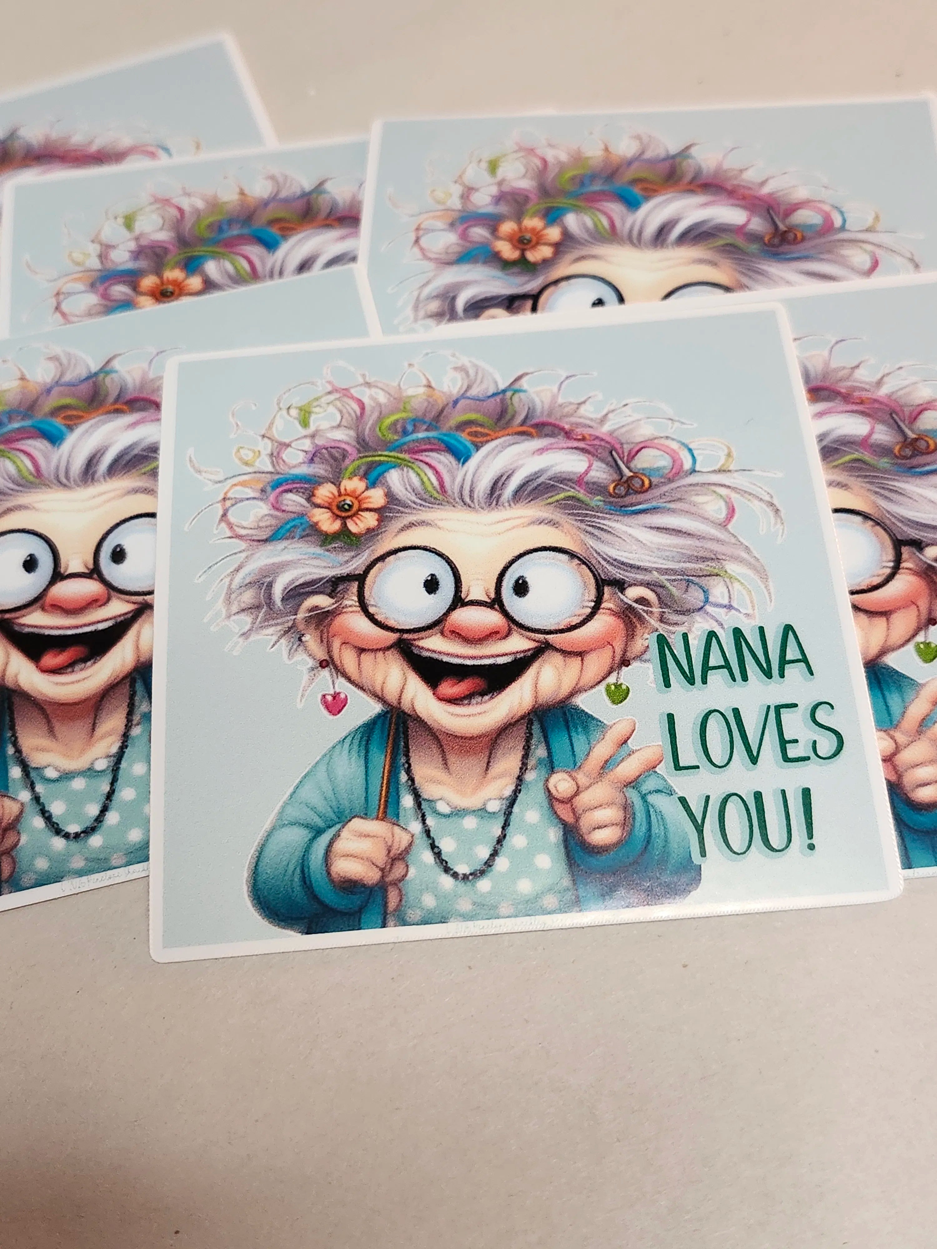 Cartoon character with colorful hair and glasses, holding a sign saying 'Nana Loves You!' on a light blue background.