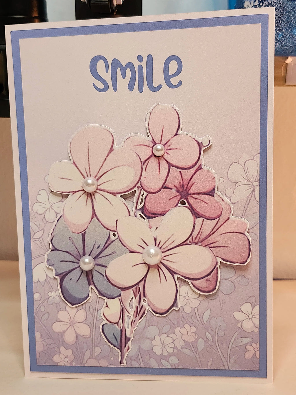 Card with pink flowers and the word 'smile' on a light background