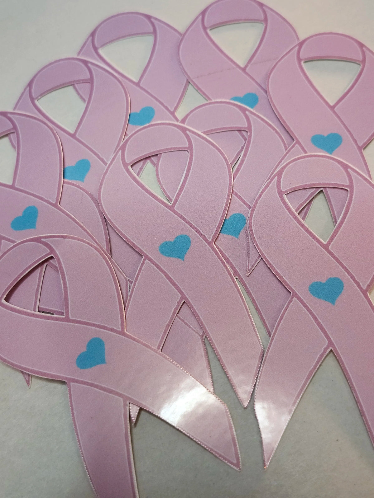 Pink ribbons with blue hearts on a light gray background