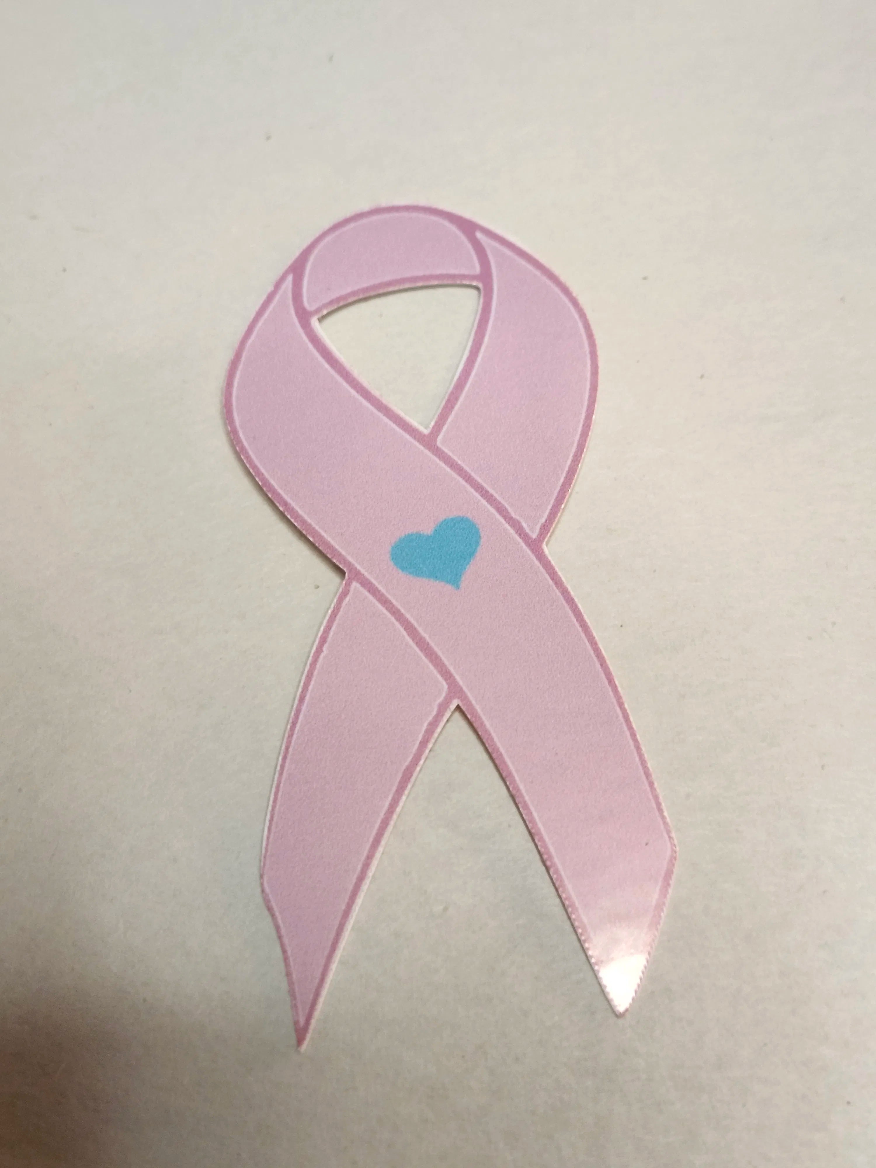 Pink ribbon with a blue heart on a light gray background