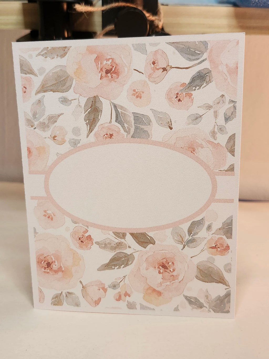 Floral patterned card with a blank oval center on a white background