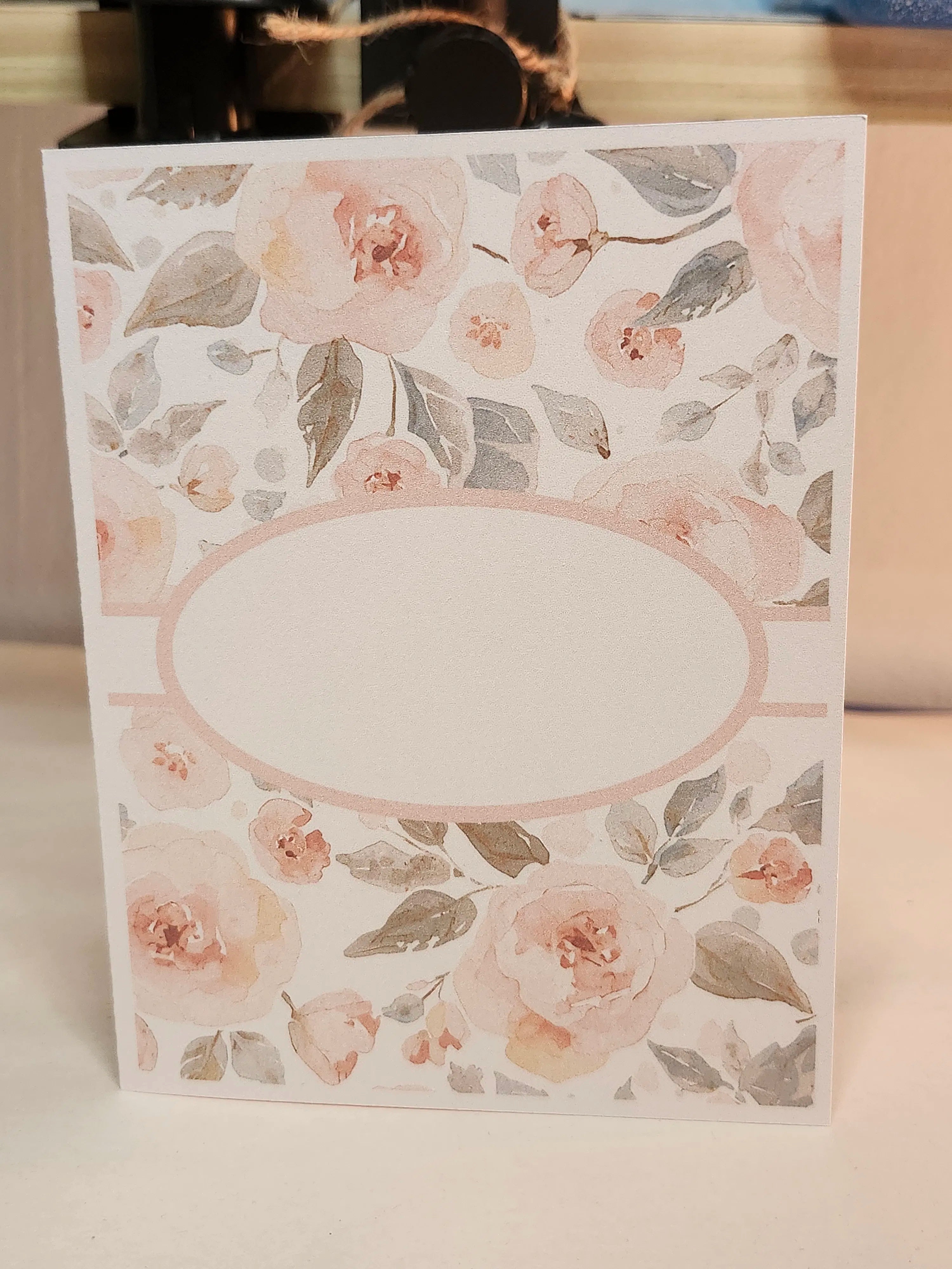 Floral patterned card with a blank oval center on a white background