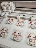 Printed illustrations of cute cartoon bunnies on a sheet with a printer in the background.