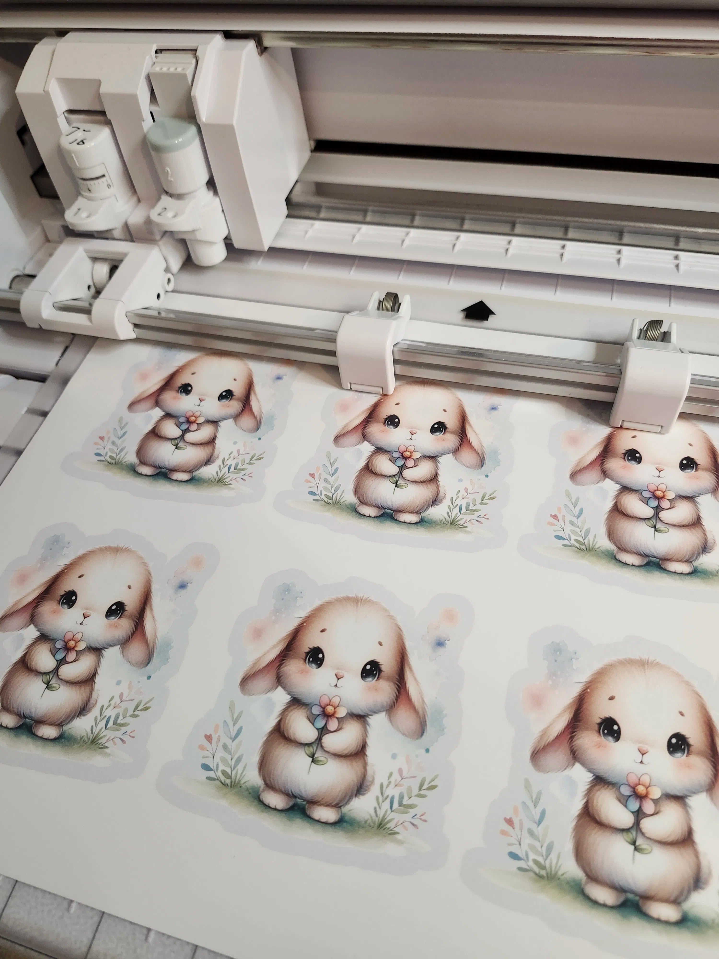 Printed illustrations of cute cartoon bunnies on a sheet with a printer in the background.