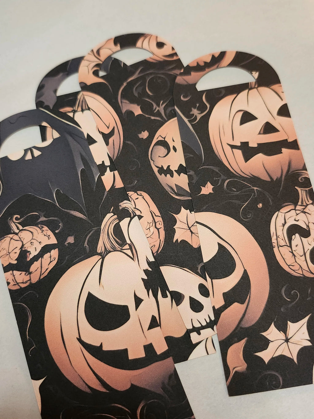 Halloween-themed bookmarks with pumpkin designs on a light gray background