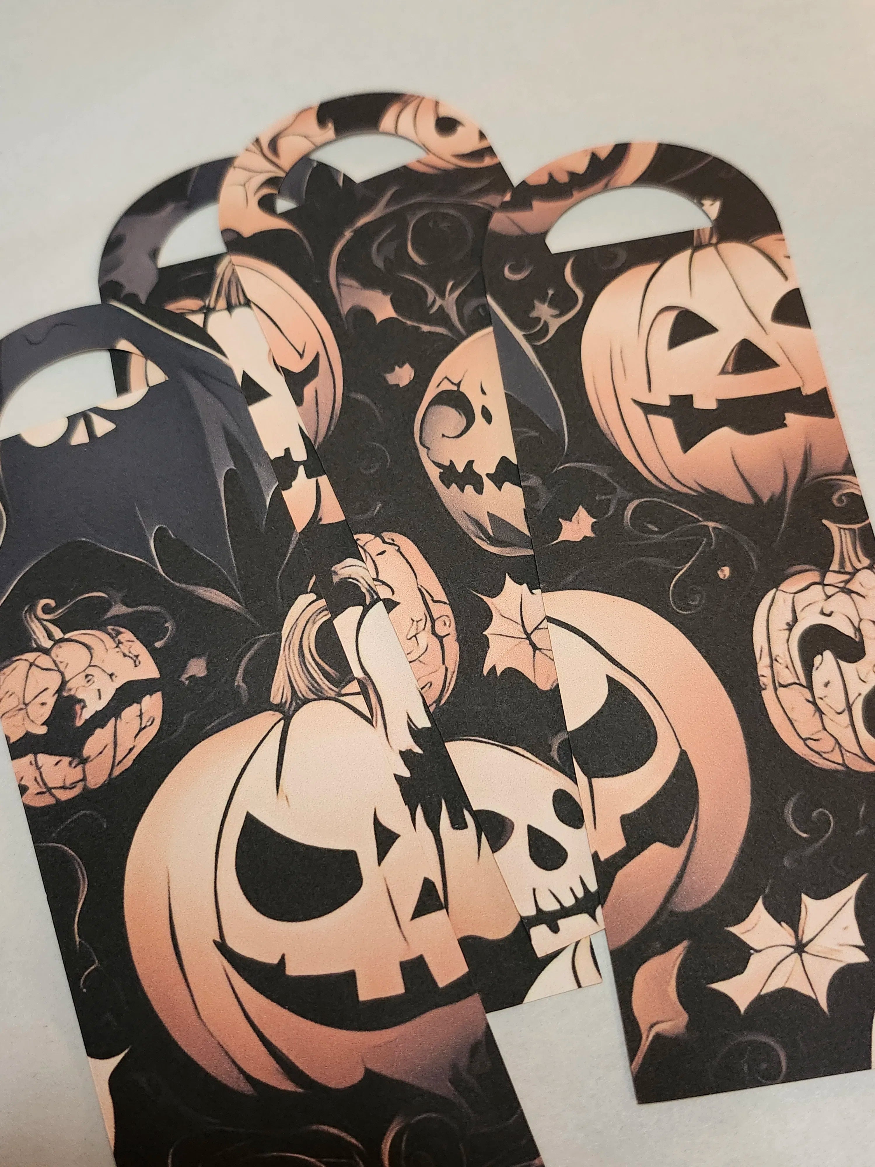 Halloween-themed bookmarks with pumpkin designs on a light gray background