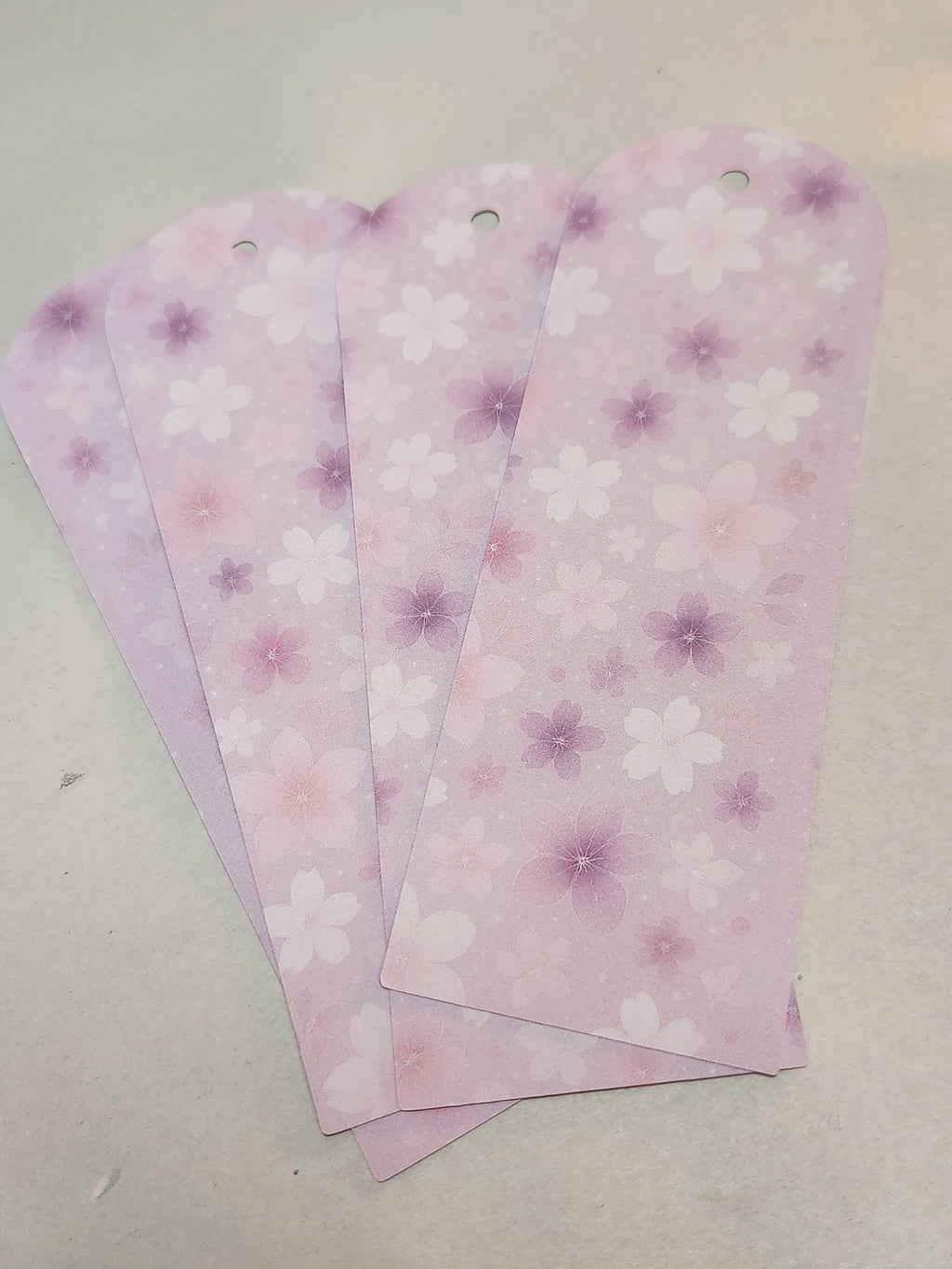 Three pink floral patterned bookmarks on a light gray background