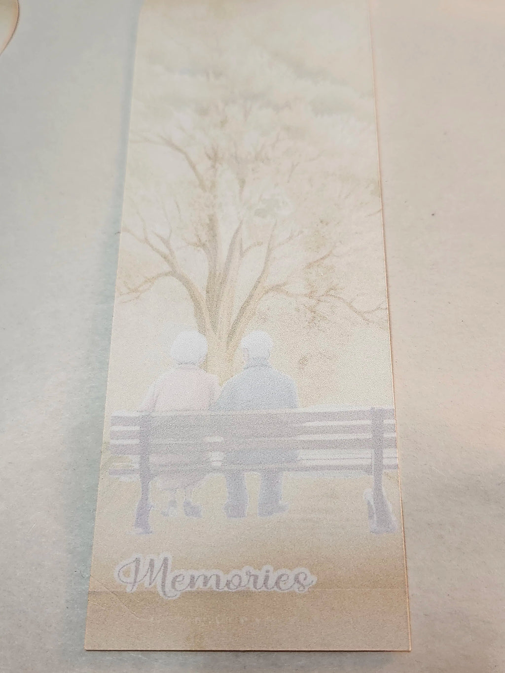 Silhouette of two people on a bench with 'Memories' text, on a textured beige background