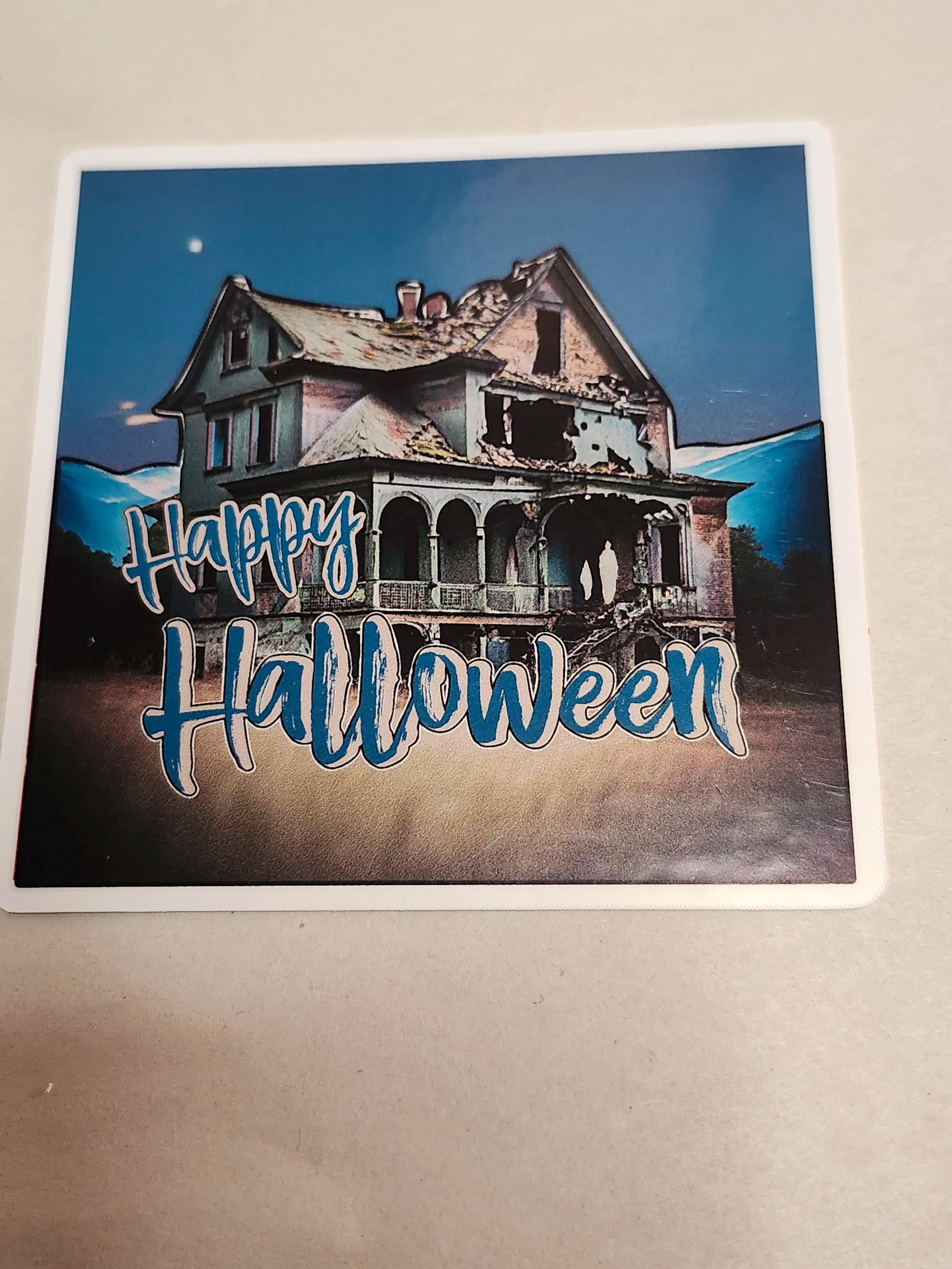 Halloween-themed sticker with a haunted house and 'Happy Halloween' text on a blue background.