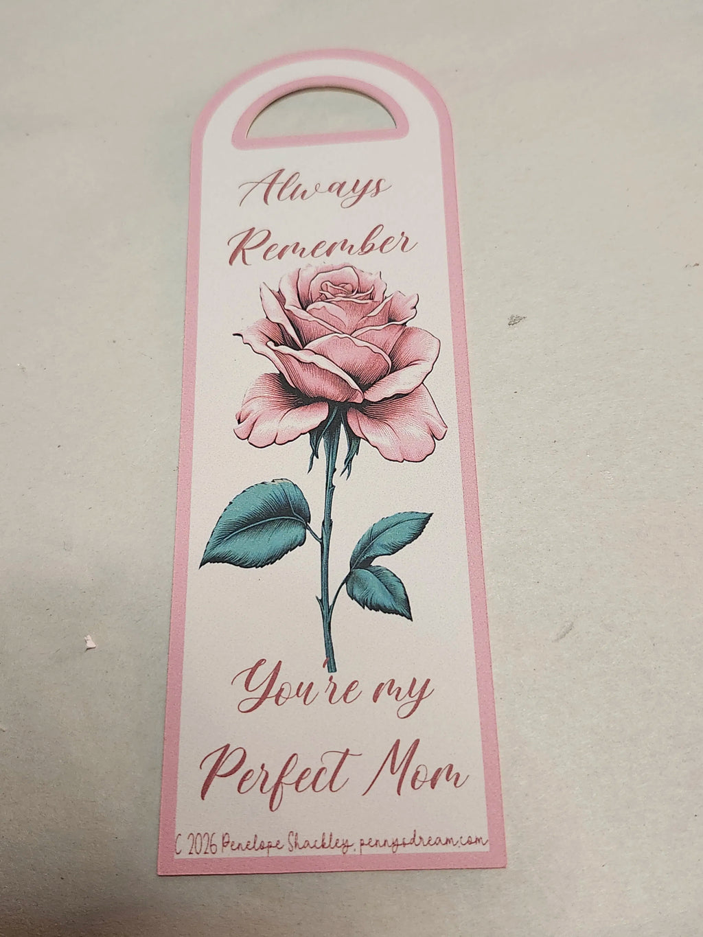 Decorative bookmark with a pink rose and text on a beige background