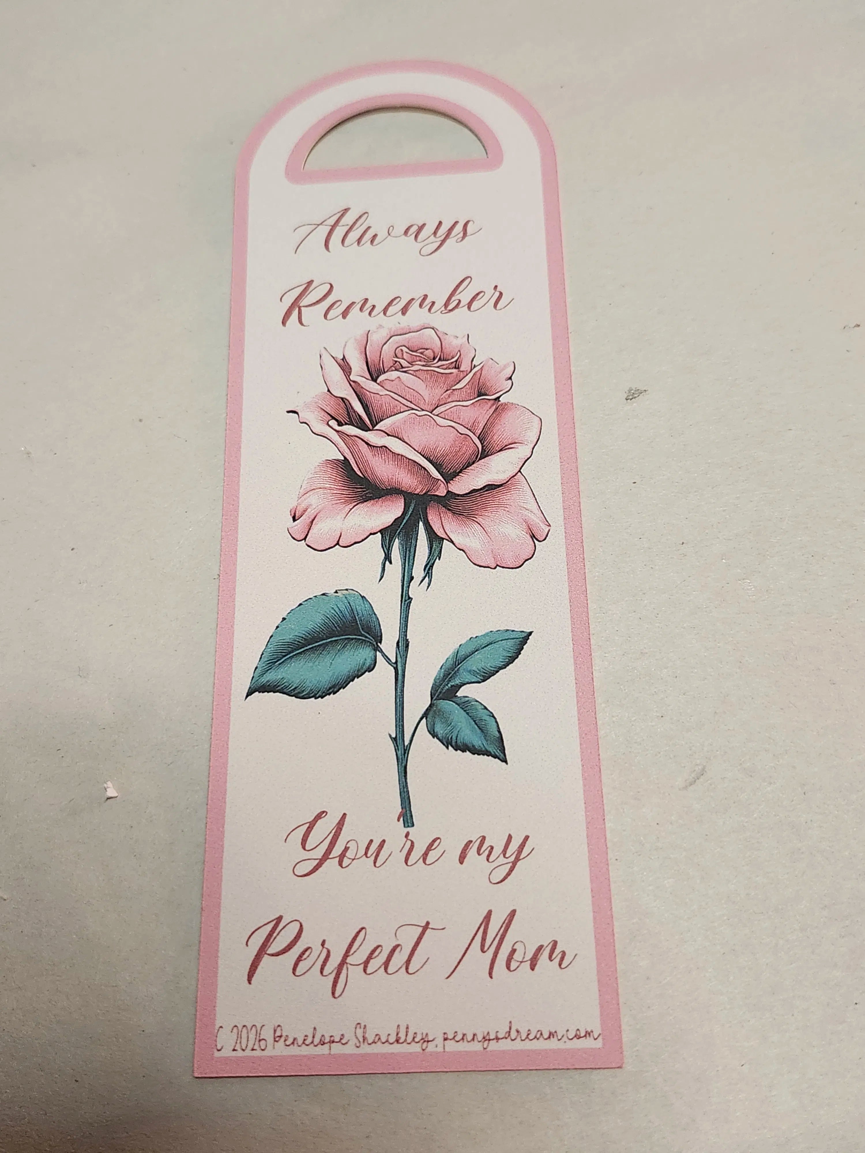 Decorative bookmark with a pink rose and text on a beige background