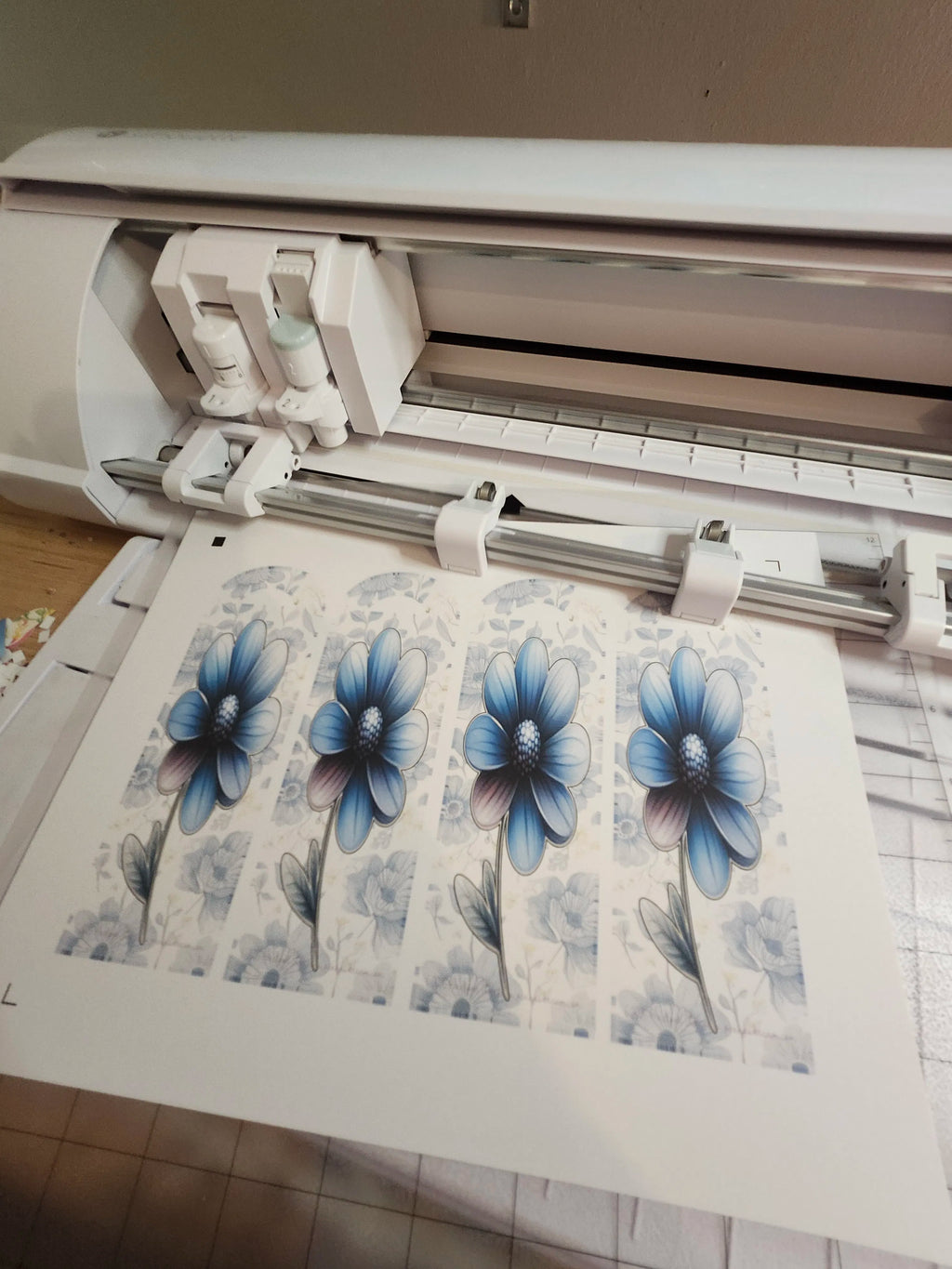 Cutter machine with blue flower designs on a sheet of paper