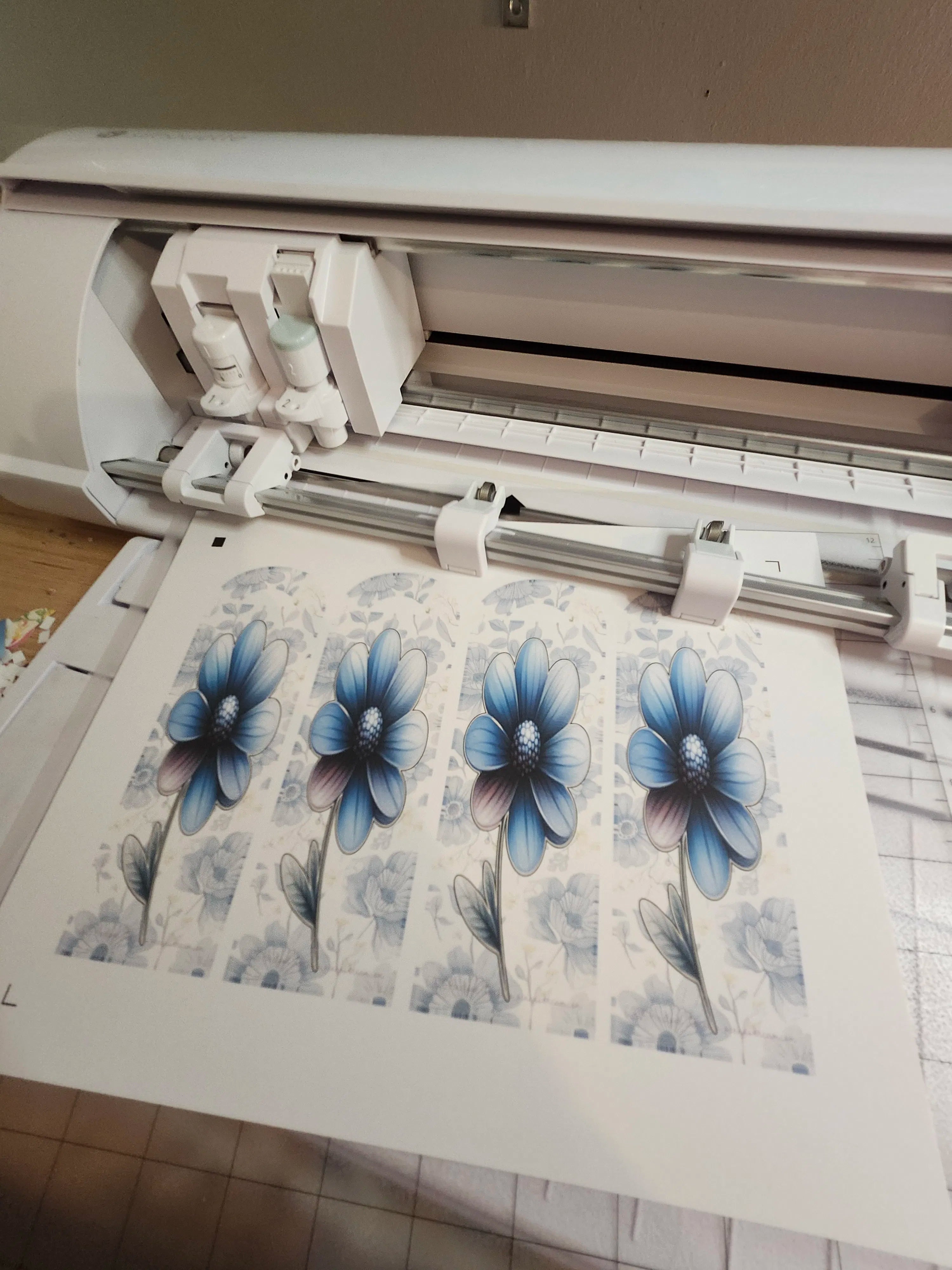 Cutter machine with blue flower designs on a sheet of paper