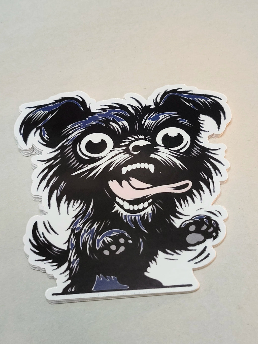 A die-cut vinyl sticker featuring a stylized black and white cartoon dog with blue shading, shown on a plain light beige background.