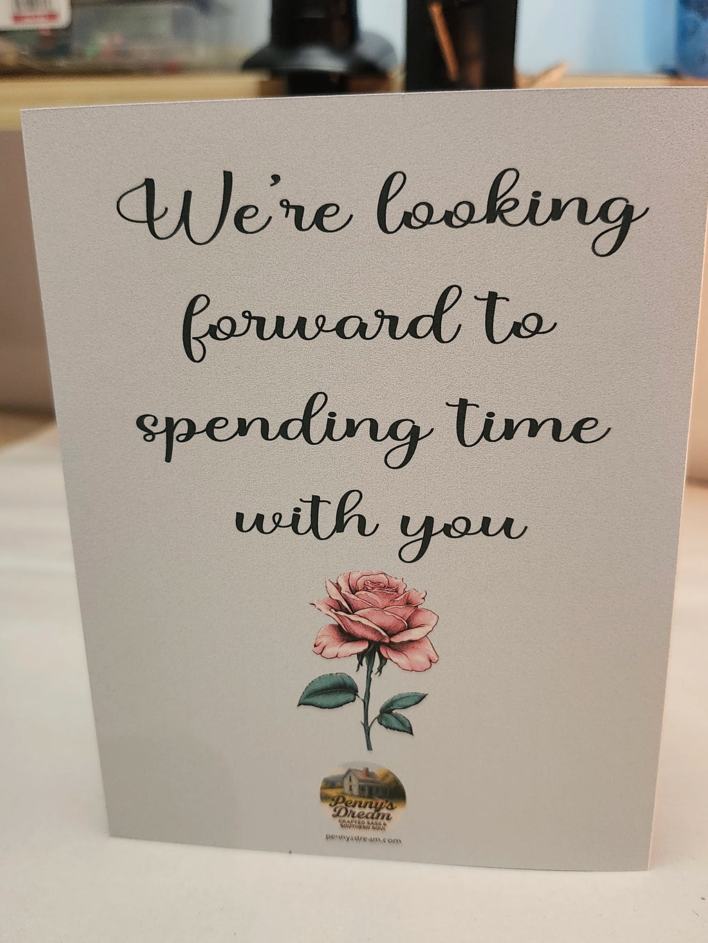 A square greeting card with a white background featuring the printed phrase 'We're looking forward to spending time with you' in black script, a pink rose illustration, and a small 'Bump & Brake' logo at the bottom.