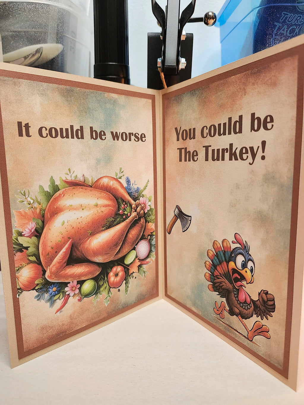 A folded greeting card or print shown open, with two illustrated sides featuring a roasted turkey and a cartoon turkey. The left side reads 'It could be worse' and shows a large turkey with flowers and vegetables.