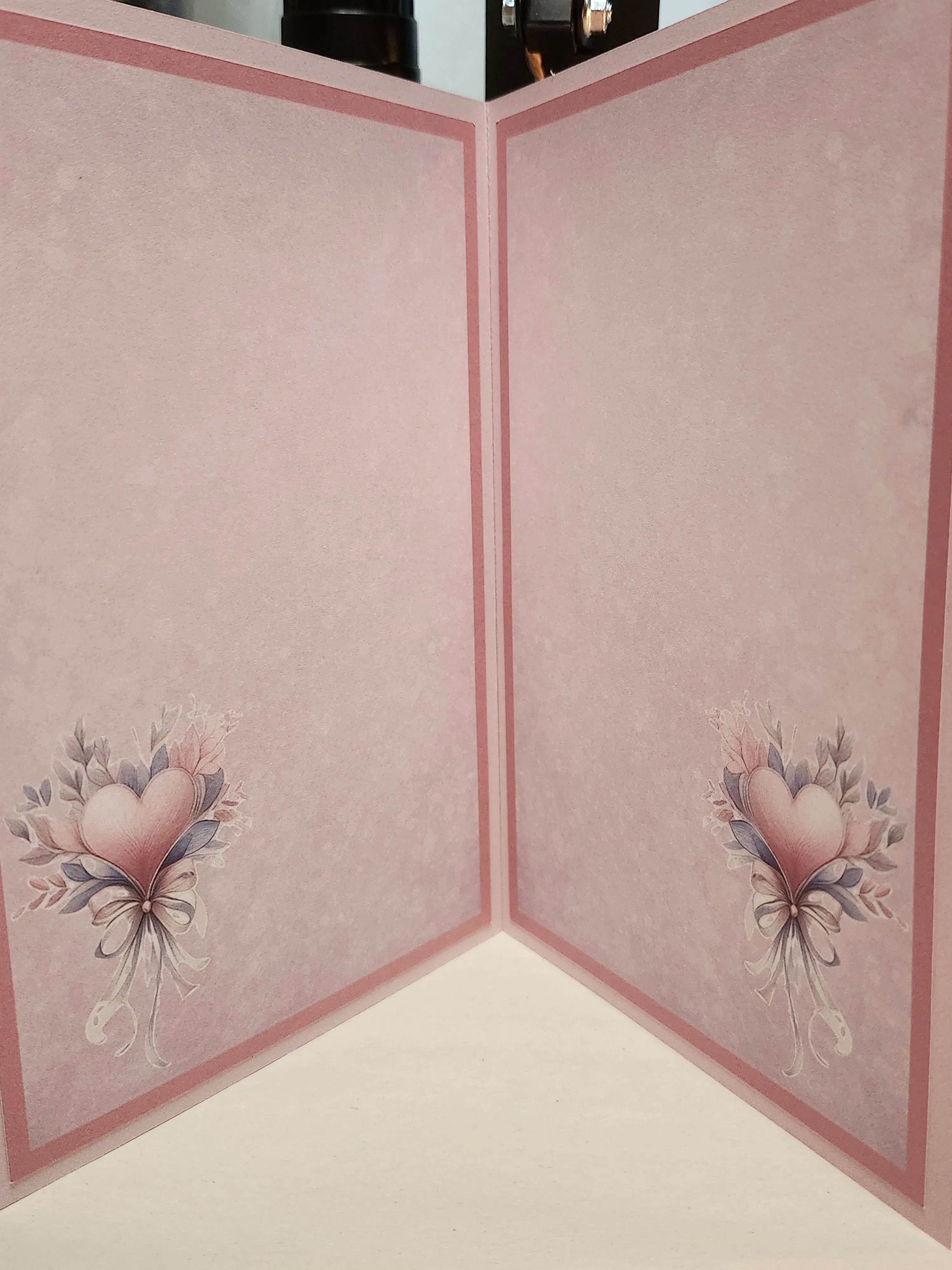 Pink cardstock craft paper with a textured pattern, featuring a pink border and a heart-shaped floral bouquet illustration in the bottom corners.