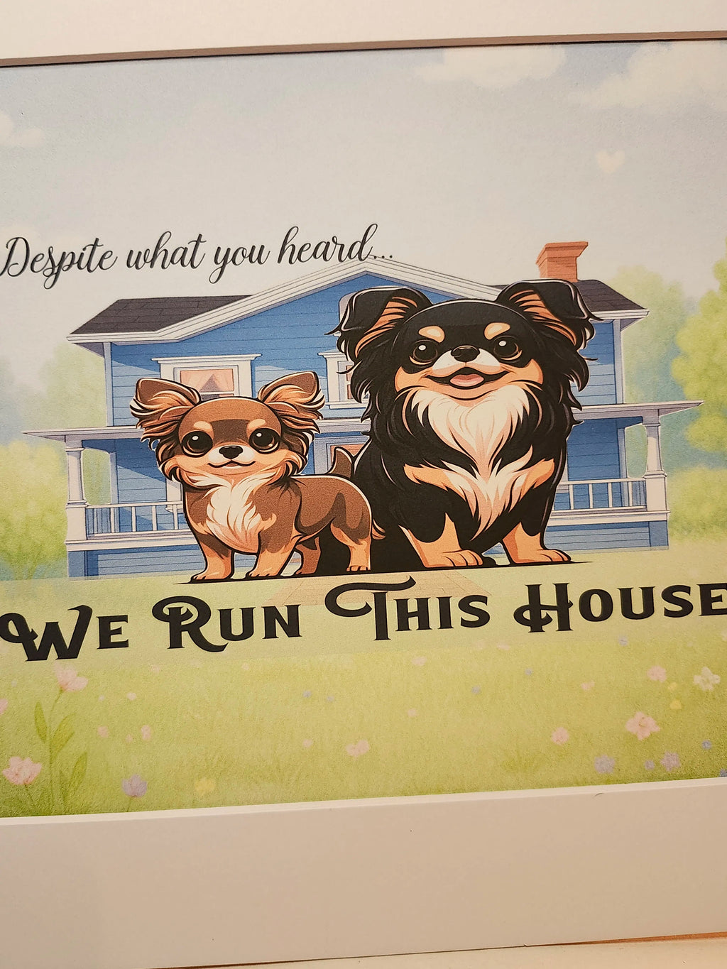 A framed art print featuring two cartoon Chihuahua dogs standing in front of a blue house with the text 'Despite what you heard.