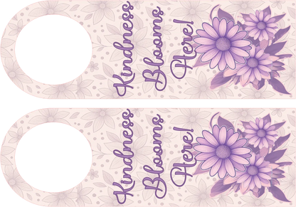 Decorative door hanger with purple flowers and 'Kindness Blooms Here!' text on a light pink background.
